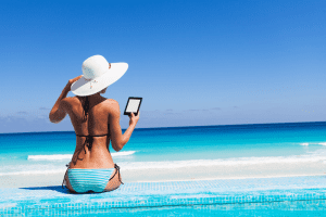 woman sitting near the pool while reading kindle